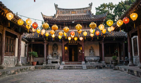 Small golden lanterns glowing above a temple courtyard at dusk